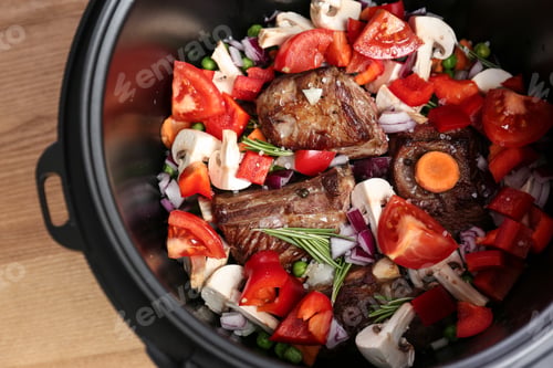 Preview: Delicious pork ribs with vegetables in multi cooker on table, closeup