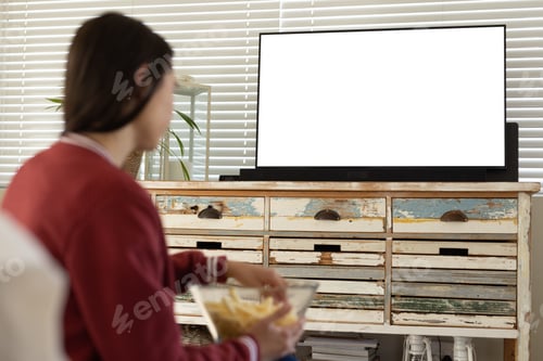 Preview: Caucasian young woman having french fries and watching tv while sitting at home, copy space
