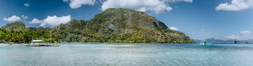 Preview: Panoramic view of El Nido bay on tranquil sunny day. Picturesque coastline with palm trees, sandy