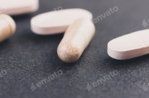 Preview: Closeup shot of white pills isolated on black background