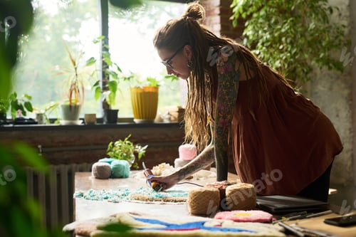 Preview: Young Adult Woman Creating Handmade Carpet in Sunlit Workshop