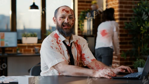 Preview: Ugly dirty office zombie sitting at desk while working on modern laptop.