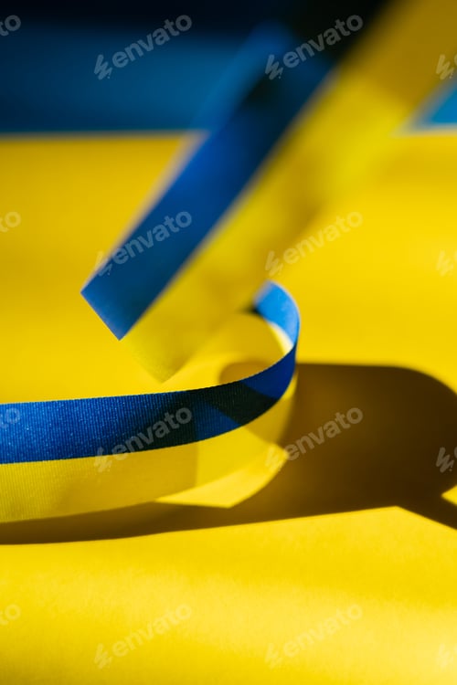 Preview: Close up view of blurred blue and yellow ribbon with shadow on ukrainian flag