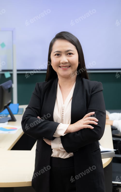Preview: A woman in a black suit and white shirt is smiling and standing with her arms crossed. Boss