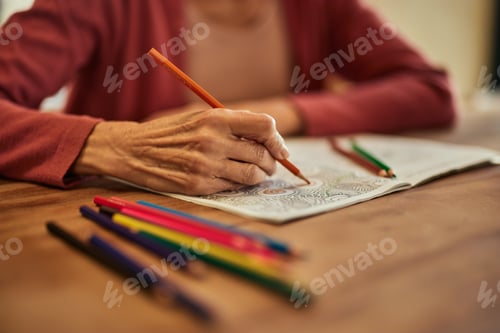 Preview: Close-up of a mature woman using crayons and coloring the coloring book.