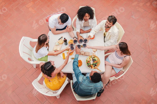 Preview: High angle view of a group of friends having a dinner party celebration at home terrace, toasting or