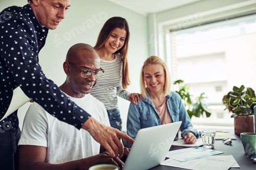 Preview: Smiling diverse businesspeople talking together over a laptop