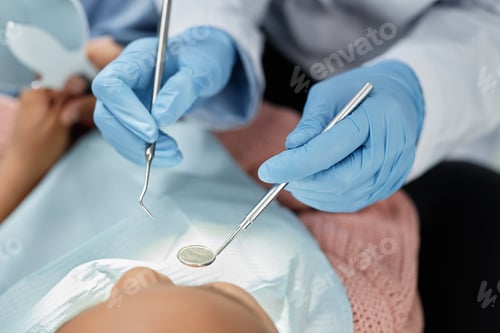 Preview: Closeup of dentist holding tools and mirror working with child