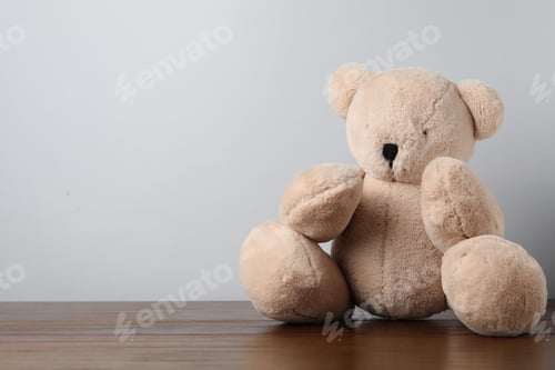 Preview: Cute teddy bear on wooden table against light background. Space for text
