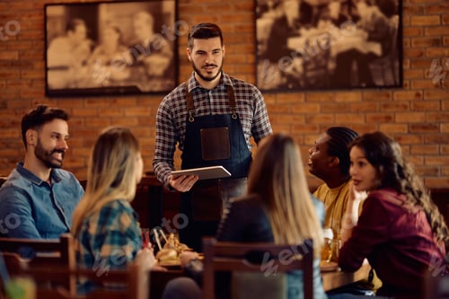 Preview: Young waiter taking order from group of customers while working in a pub.