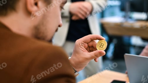 Preview: Worker holding a physical cryptocurrency coin in an office