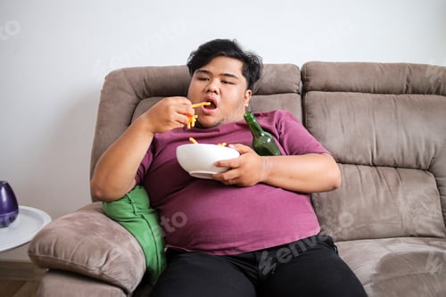 Preview: Overweight Man Lounging on Couch With Fries and Beer Enjoying Lazy Day at Home