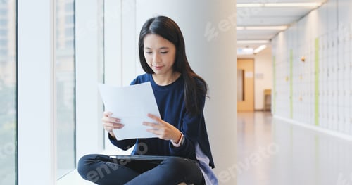 Preview: Woman reading on paper note in university campus