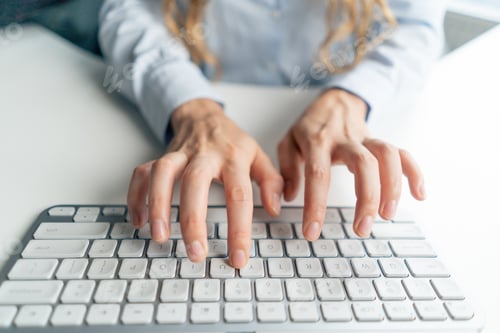 Preview: top shot close-up in a modern office female worker in a blue shirt sitting at a table directly