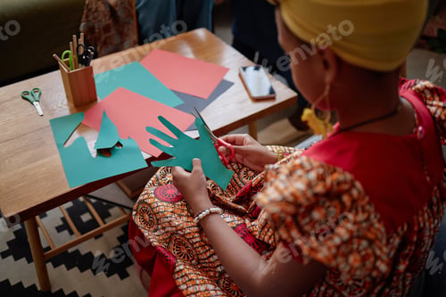 Preview: Young Black Girl Creating Kwanzaa Handcrafts Using Colored Paper at Table