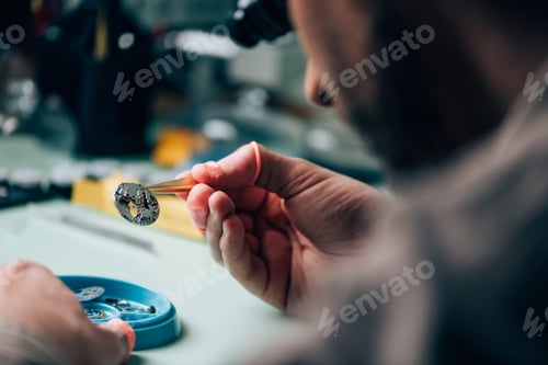 Preview: Selective focus of watchmaker holding watch part by tool tray on table