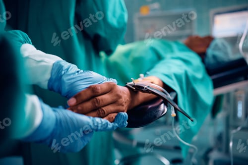 Preview: Close up of surgical nurse holding patient's hand in operating room.
