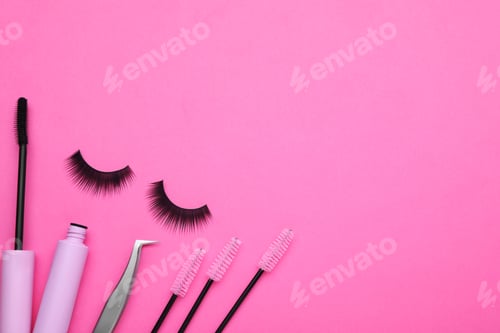 Preview: Fake eyelashes, brushes and tweezers on pink background, flat lay. Space for text
