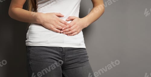 Preview: a young woman with bellyache or menstrual cramps holding her stomach.
