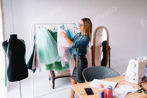 Preview: Attractive female fashion designer is working in her workshop.