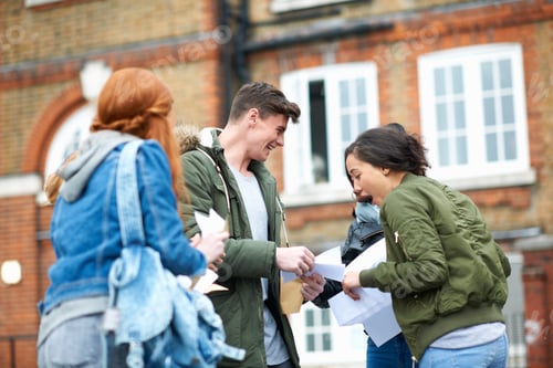 Preview: Happy male and female college students reading exam results on campus