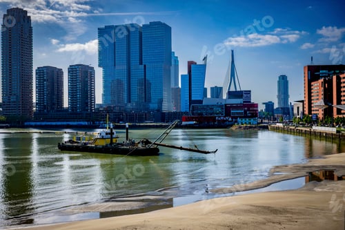 Preview: Bustling city skyline against a clear blue sky with a tugboat on the river