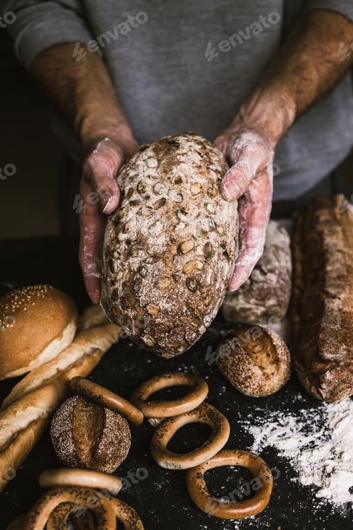 Preview: Baker man holding a rustic organic loaf of bread in his hands