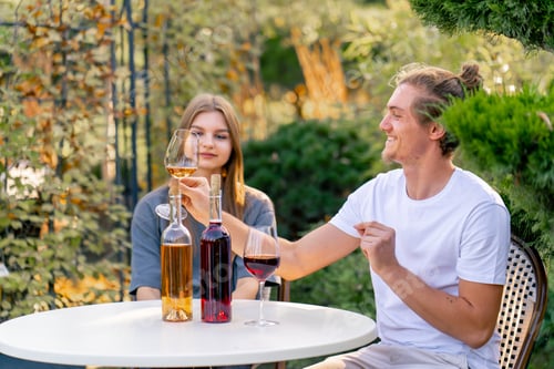 Preview: A couple are sitting together in the garden of winery clinking glasses of different types of wine