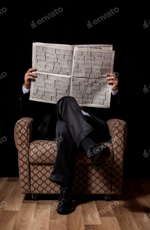 Preview: Man with newspaper sitting in vintage armchair