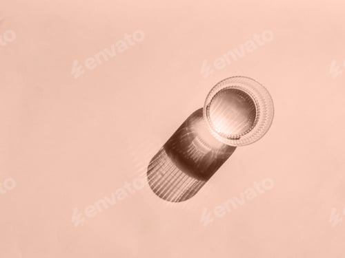 Preview: Glass of water and long shadow from sunlight on beige background
