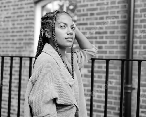 Preview: Monochrome portrait of young woman leaning on a fence.