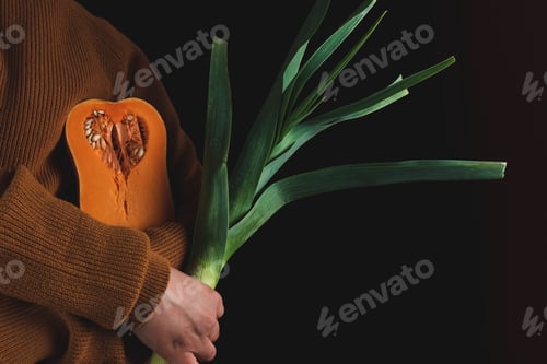 Preview: Closeup view of a person holding scallion and a pumpkin shaped like lungs - health concept