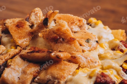 Preview: Closeup shot of a dish with french fries, sausages topped with cheese and corn on a wooden table.