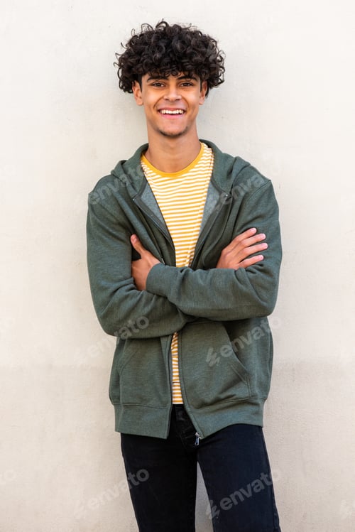 Preview: smiling young handsome man with arms crossed by white wall