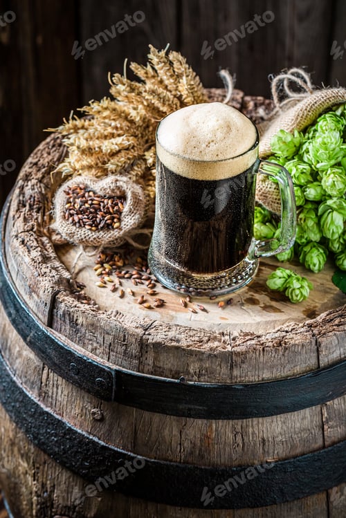 Preview: Brewing industry. Dark beer with foam on oak barrel.