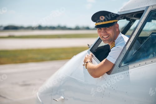Preview: Cheerful young pilot sitting inside plane cockpit