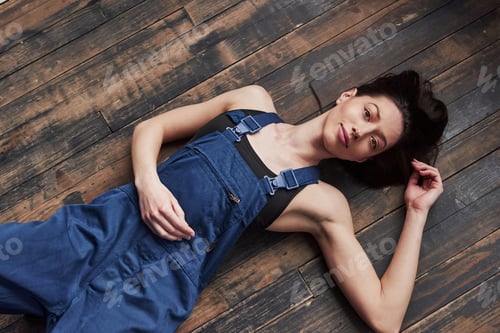 Preview: Top view. Girl in the blue uniform for the work is lying on wooden floor having relax