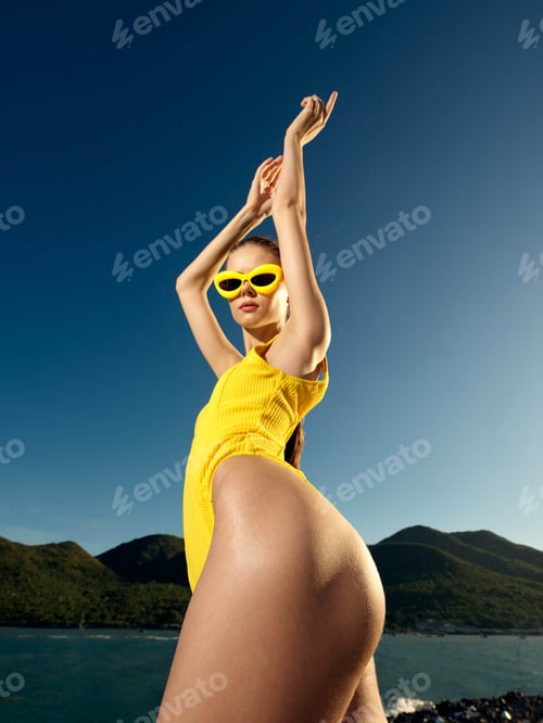 Preview: Beach, swimwear, posing, confident a woman in a yellow swimsuit confidently poses on the beach with
