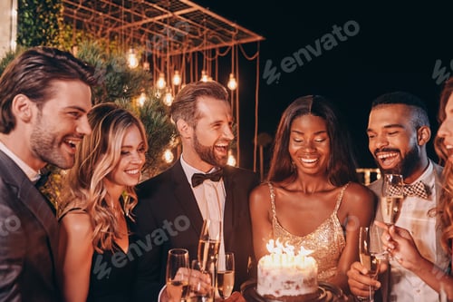 Preview: Group of people in formalwear holding birthday cake while spending time on party