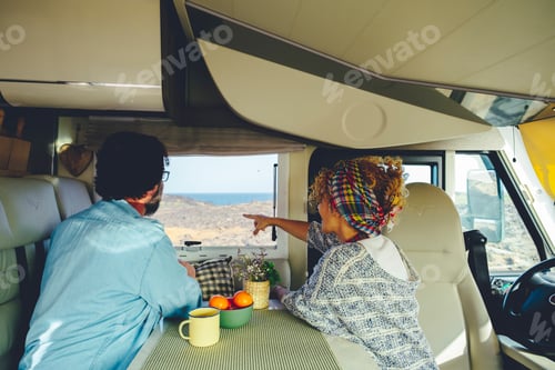 Preview: Back view of a couple admiring the nature outdoors view outside the windows from camper