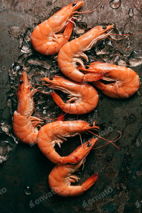 Preview: elevated view of pile of shrimps with melting ice on rustic table