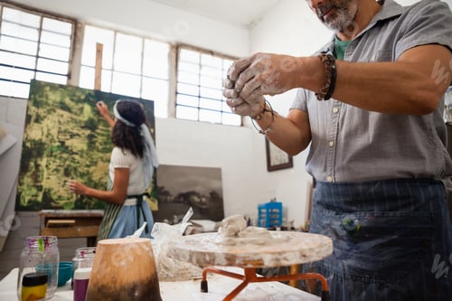 Preview: Man molding clay while woman painting on canvas