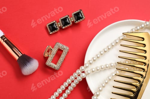 Preview: Different hair clips, pearl necklace, brush and comb on red background, flat lay