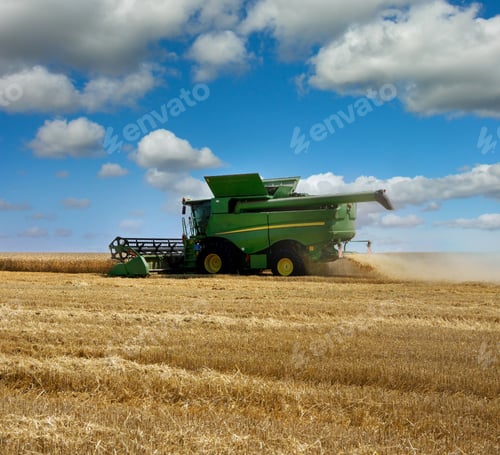 Preview: combine harvester during wheat harvest under a sky with clouds.