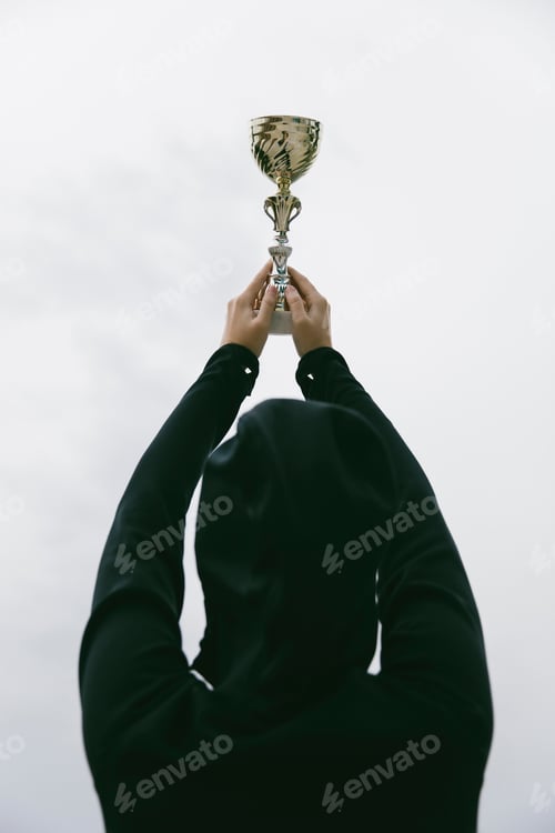 Preview: Happy sporty young woman holding gold trophy cup