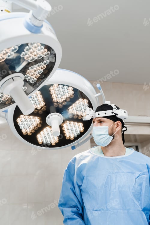 Preview: Male surgeon prepares for surgery wearing headlight in operating room clinic setting