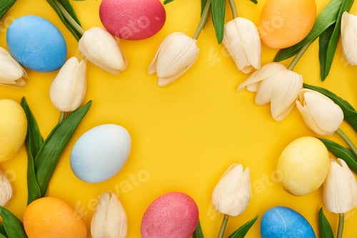 Preview: top view of tulips and painted Easter eggs on colorful yellow background with copy space