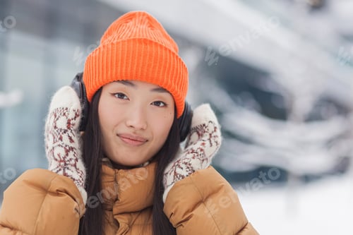 Preview: Close-up portrait of a young beautiful Asian woman looking at the camera and smiling while listening