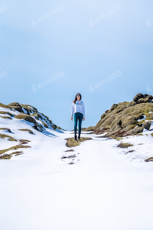 Preview: Woman with her back on a snowy road on a sunny day in Iceland