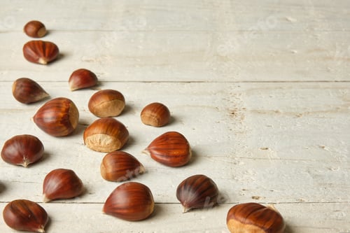 Preview: chestnuts distributed in the lower left corner of the image on a white rustic table